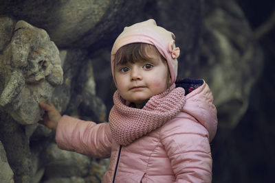 Portrait of cute girl standing by rock formation