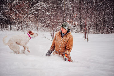 Woman playing with dog on snow