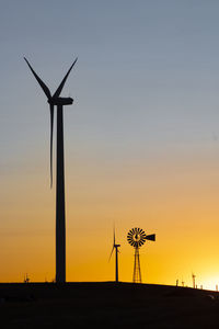 Looking up at wind turbine next to a windmill