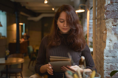 Woman reading menu while sitting in cafe