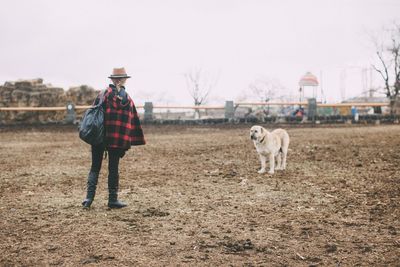 Rear view of cowgirl standing in front of dog