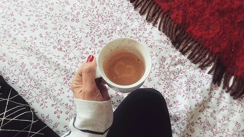 High angle view of woman holding coffee cup on table