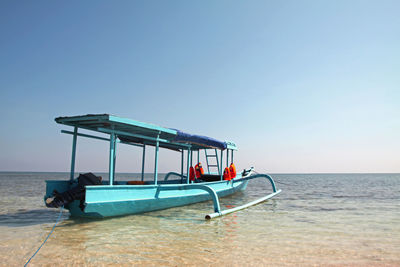 Boat on shore against clear blue sky