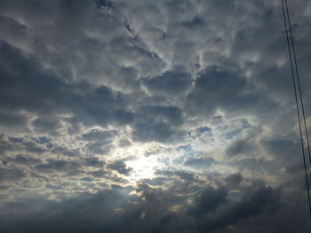 Low angle view of sunlight streaming through clouds