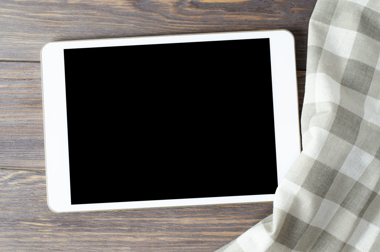 CLOSE-UP OF SMART PHONE ON TABLE IN EMPTY ROOM