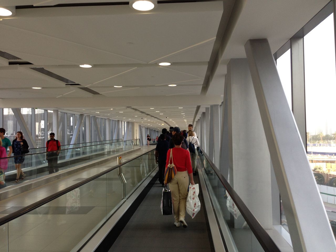 indoors, architecture, lifestyles, built structure, ceiling, men, person, walking, leisure activity, railing, full length, rear view, standing, modern, travel, large group of people, railroad station, corridor