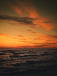 Scenic view of sea against dramatic sky during sunset