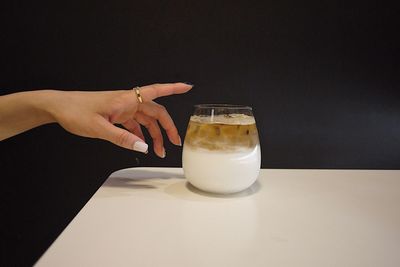 Close-up of hand holding drink on table