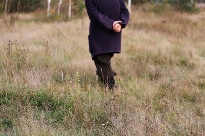 Freedom old woman, female person walking in autumn meadow. fall dry grass. people leaving home, lost