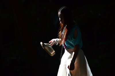 Woman looking away while standing against black background