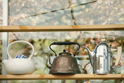 Close-up of kettles on wooden shelf