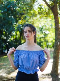 Young woman standing against trees