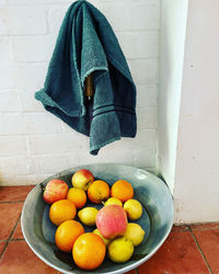 Fruits in container on table against wall