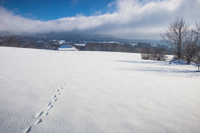 Scenic view of snow covered field against sky