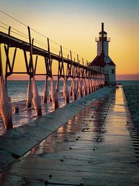 Pier on sea against sky at sunset