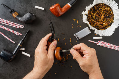 Cropped image of hands cleaning smoking pipe at table