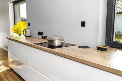 Steel pots with a cooking dish on an induction cooker built into the kitchen worktop on the cabinets