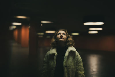 Young woman looking up while standing in garage