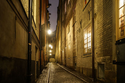 Empty alley amidst buildings at night