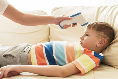 Cropped hand of woman checking temperature of son at home