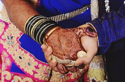 Midsection of bride and groom holding hands