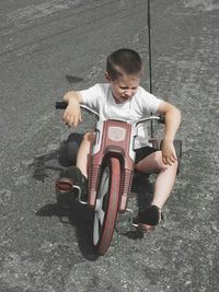 High angle view of cute boy riding toy motorcycle on road