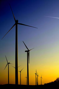 Low angle view of wind turbines on field against sky