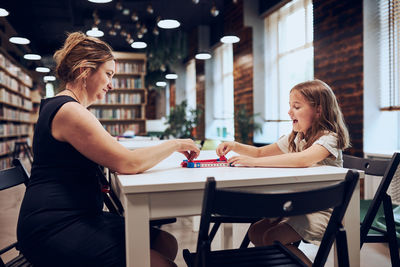 Teacher playing with student board game in after school club. child spending time playing game