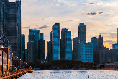 Modern buildings by river against sky in city