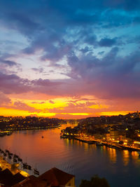Scenic view of river by buildings against sky during sunset