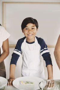 Portrait of happy boy preparing food with parents at table in kitchen