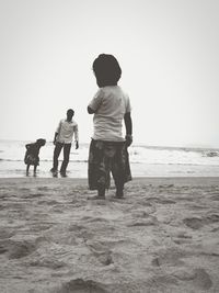 Full length of father and daughter walking on beach