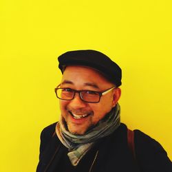 Portrait of smiling young man against yellow background