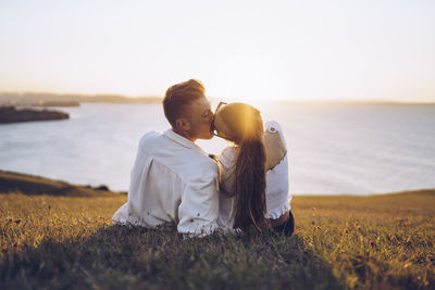 Rear view of couple kissing in sea against sky