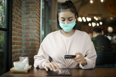 Young woman using tablet on table at window