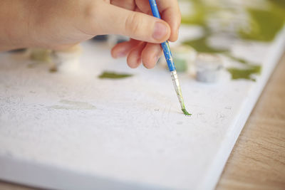 Cropped hand of person painting on table