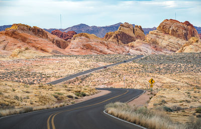 Scenic view of road by mountains against sky