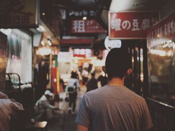 Rear view of people walking on illuminated city