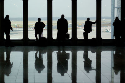 Silhouette people by window against sky