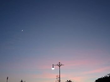 Low angle view of silhouette communications tower against sky at sunset