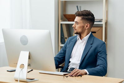 Portrait of businessman using laptop at desk in office