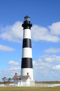 Lighthouse on landscape against cloudy sky