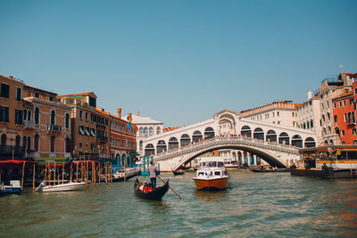 Boats moored in canal against buildings in city