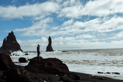 People standing on rock by sea against sky