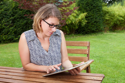 Young woman sitting on book in park