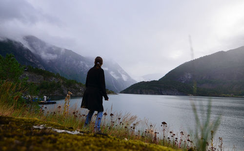 Woman walking at lakeshore against mountains