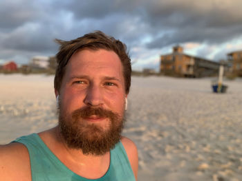 Portrait of bearded man on beach with headphones.