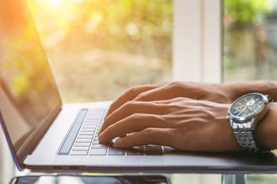 Cropped image of hands working laptop