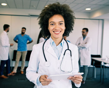 Portrait of smiling female doctor holding digital tablet