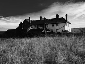 Abandoned building on field against sky at dusk